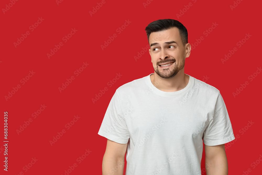 Handsome ashamed young man on red background Handsome ashamed young man on red background