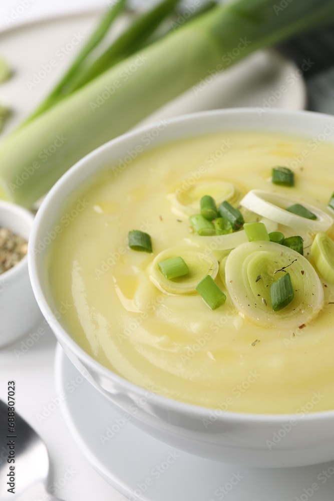 Bowl of tasty cream soup with leek on white table, closeup Bowl of tasty cream soup with leek on white table, closeup