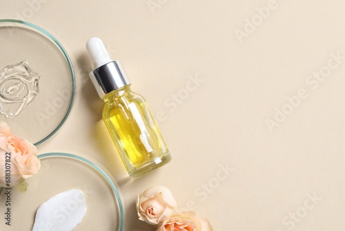 Bottle of cosmetic serum, flowers, petri dishes with samples on beige background, flat lay. Space for text