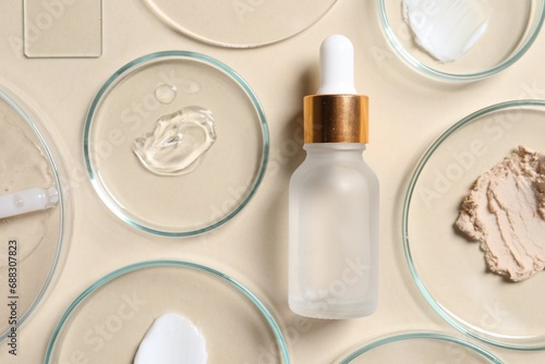 Bottle of cosmetic serum and petri dishes with samples on beige background, flat lay