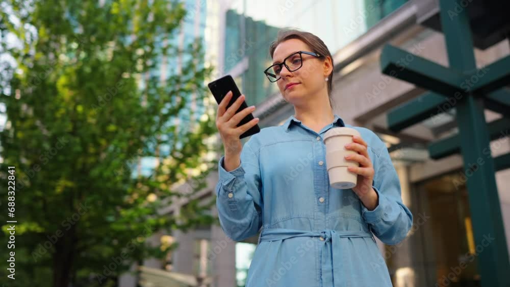 Caucasian woman in glasses stands on the street and using smartphone Caucasian woman in glasses stands on the street and using smartphone