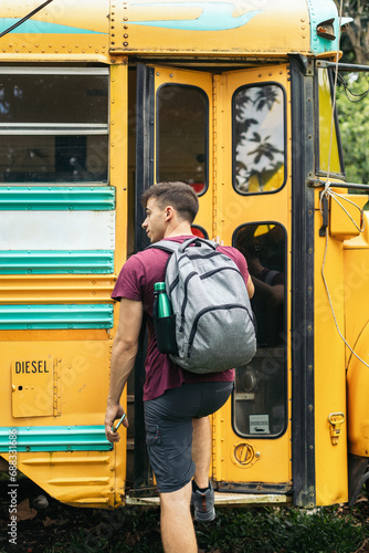 Guy with backpack entering a yellow school bus