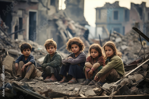 Group of children in dirty clothes sitting in the middle of destroyed city by war