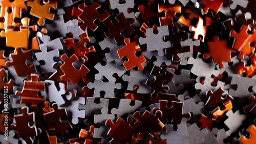 Background of Colored Puzzle Pieces that Rotating Counterclockwise - Top View. Texture of Incomplete Red and Grey Jigsaw Puzzle with Low Key Light - Left Rotation photo