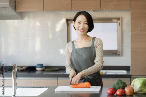 綺麗なキッチンに立つ料理をする女性　左にコピースペースあり photo