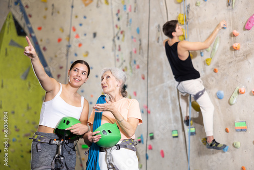Young girl and older woman with equipment getting ready to climb wall in gym