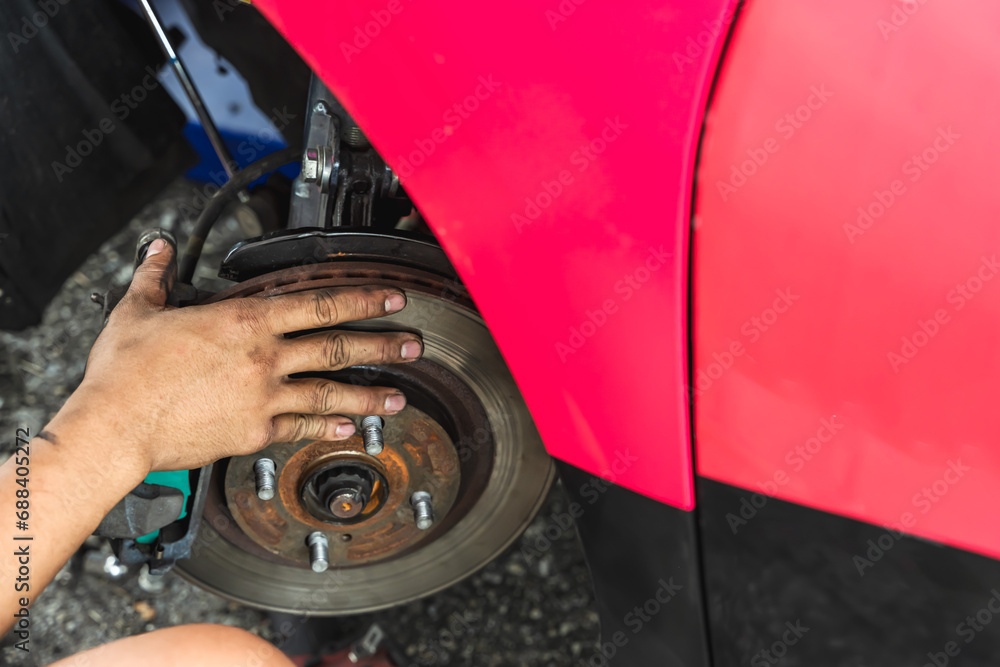 Close uo car mechanic checking break and changing car wheel in auto repair shop