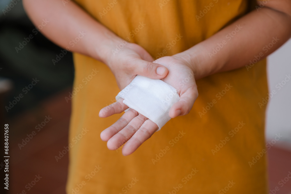 A person in a yellow top has white bandages on their hand and wrist because of a car accident. A person in a yellow top has white bandages on their hand and wrist because of a car accident.