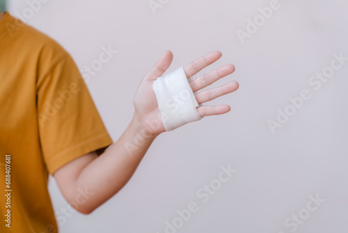 A person in a yellow top has white bandages on their hand and wrist because of a car accident.