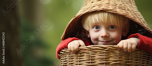 Blond boy dressed as gnome elf concealed in straw basket photo