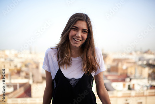 funny portrait of a young white and brunette woman smiling at the camera and with barcelona in the background photo