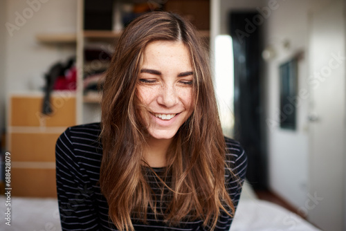 Nice woman sitting in her bedroom laughing with her eyes closed photo