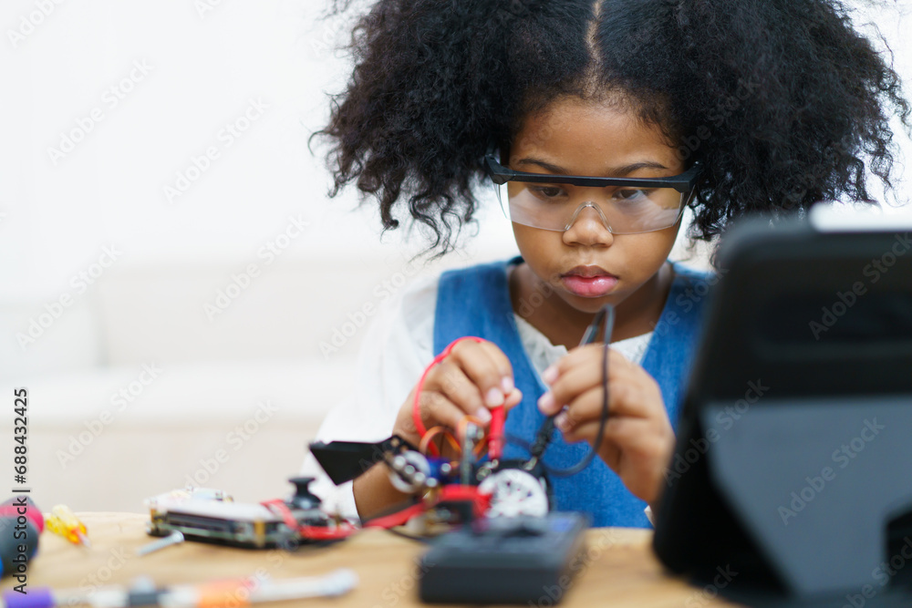 Little girl learns to assemble a robot toy. Little girl learns to assemble a robot toy.
