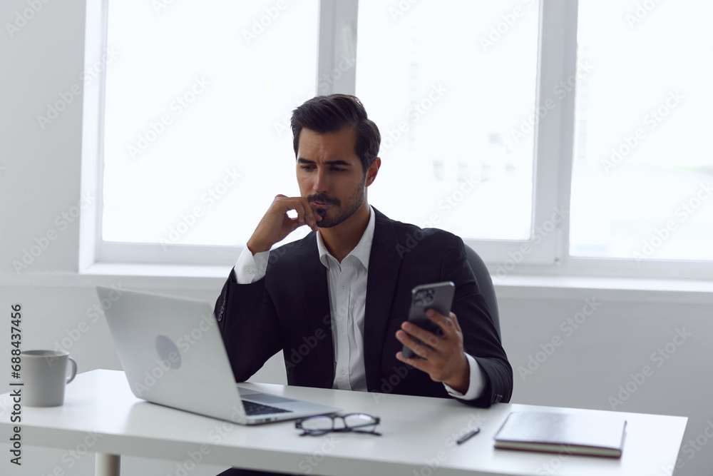 Man in office businessman sitting at desk and working in laptop and talking on phone, modern suit, finance and startup concept and data analysis, working lifestyle in bright office. Man in office businessman sitting at desk and working in laptop and talking on phone, modern suit, finance and startup concept and data analysis, working lifestyle in bright office.