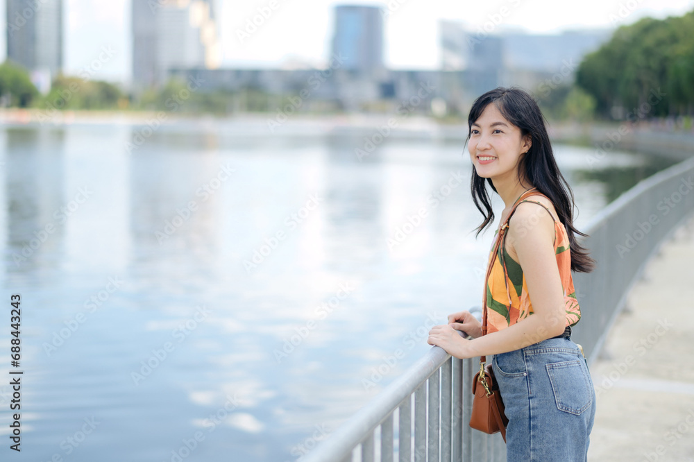 Embrace the beauty of nature at the waterfront, where a smiling lady in an orange shirt stands by lake.