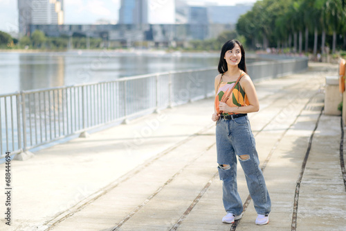 A happy young woman, enjoying a stroll on an urban path, dressed in an orange shirt.