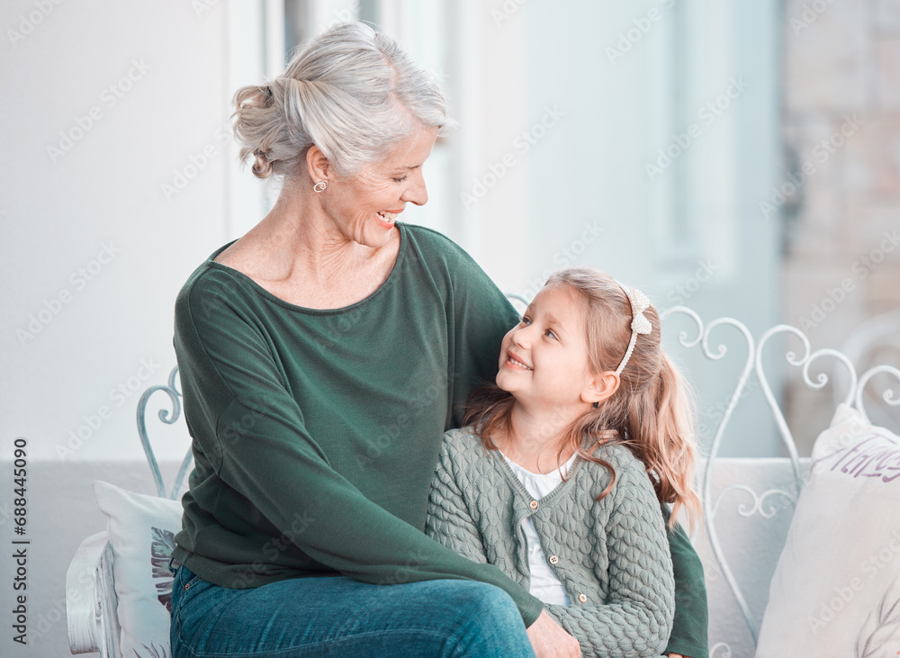 Obraz premium Grandmother, girl child and smile on sofa with hug, care or bonding for love, talk and family home lounge. Elderly lady, child and embrace with smile, relax and together on living room couch in house