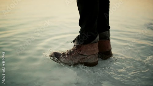 Man with leather boots walking into shallows of Dead Sea. Slow motion, close-up photo