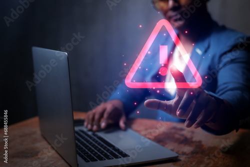 Businessman uses laptop computer with warning triangle sign or exclamation mark for error notification and technology maintenance concept.
 photo