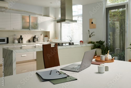 Opened laptop and folders on kitchen table  working from home concept