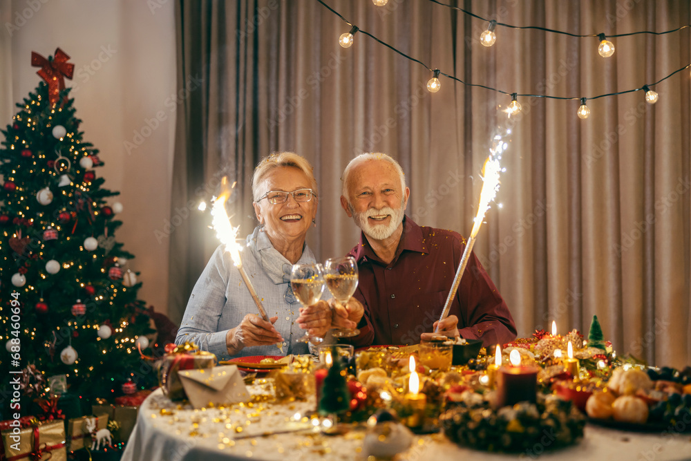 A happy senior couple is celebrating christmas and new year's eve at home with fireworks.