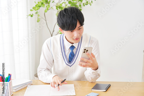 自宅でスマートフォンを使って勉強する男子高校生