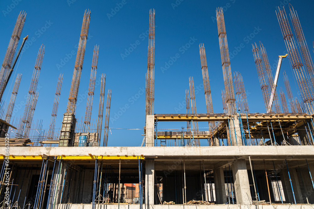 View of a large construction site with buildings under construction and multi-storey residential homes.Tower cranes in action on blue sky background. Housing renovation concept. Crane during formworks View of a large construction site with buildings under construction and multi-storey residential homes.Tower cranes in action on blue sky background. Housing renovation concept. Crane during formworks