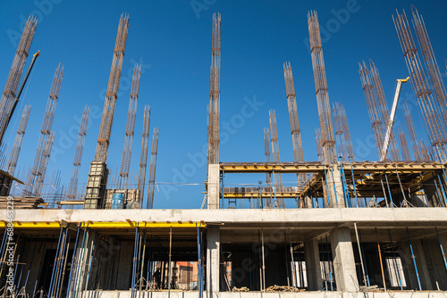 View of a large construction site with buildings under construction and multi-storey residential homes.Tower cranes in action on blue sky background. Housing renovation concept. Crane during formworks