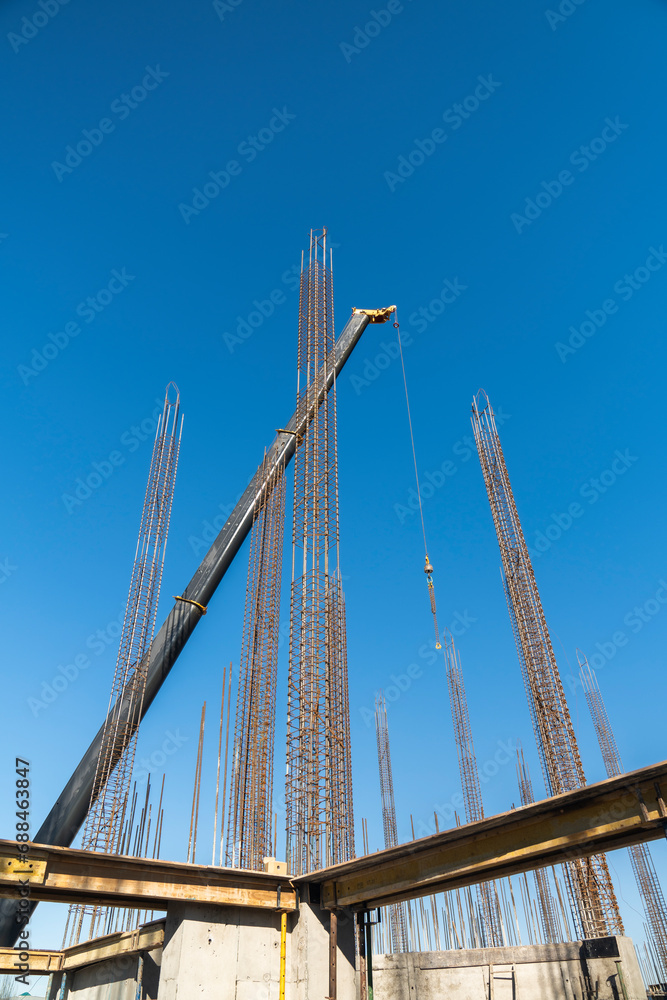 Obraz premium View of a large construction site with buildings under construction and multi-storey residential homes.Tower cranes in action on blue sky background. Housing renovation concept. Crane during formworks