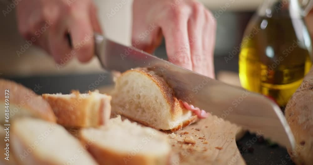 Woman slicing baguette bread on a wooden cutting board at domestic kitchen close-up Woman slicing baguette bread on a wooden cutting board at domestic kitchen close-up