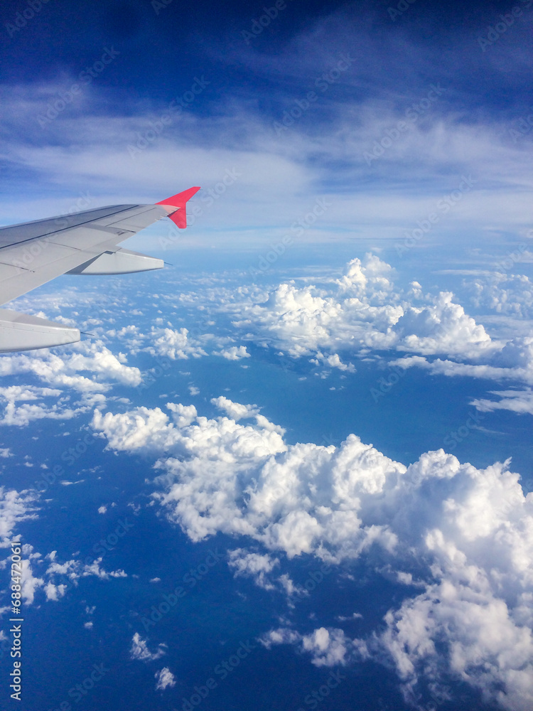 Airplane window cloudscape. An Airplane's wing in the sky taken from the window. Aircraft wing in flight through clouds. Airplane wings against a beautiful blue cloudy sky taken from inside the cabin. Airplane window cloudscape. An Airplane's wing in the sky taken from the window. Aircraft wing in flight through clouds. Airplane wings against a beautiful blue cloudy sky taken from inside the cabin.
