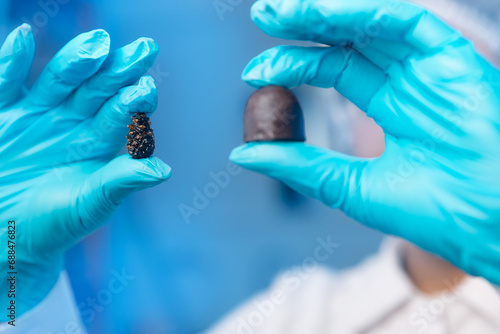Food industry, candy factory, worker chemist tests chocolate products in laboratory, blue background