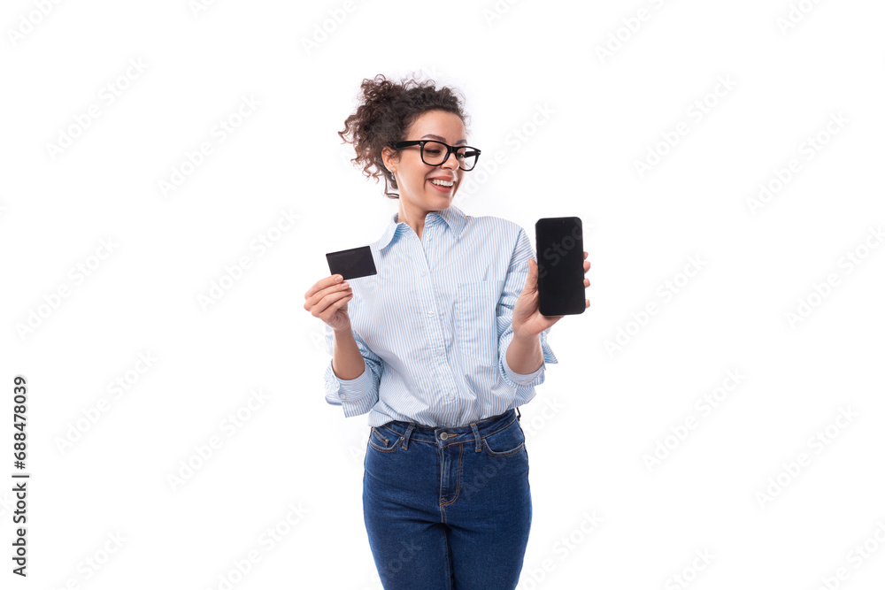 slender young brunette curly business woman dressed in a light blue shirt shows a smartphone screen and a plastic card slender young brunette curly business woman dressed in a light blue shirt shows a smartphone screen and a plastic card