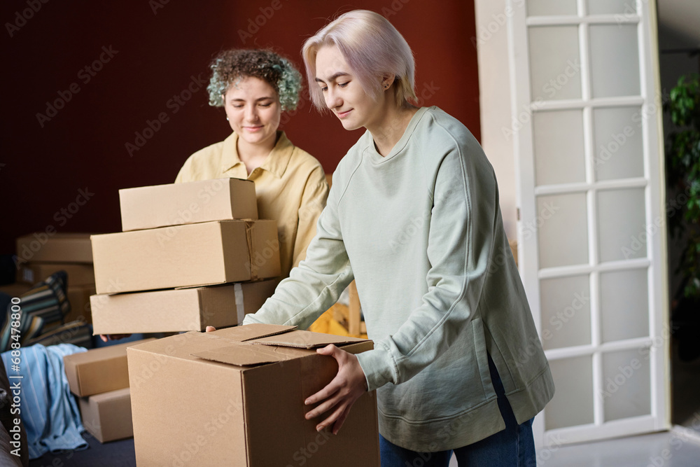 Girls carrying cardboard boxes during their move in new house Girls carrying cardboard boxes during their move in new house