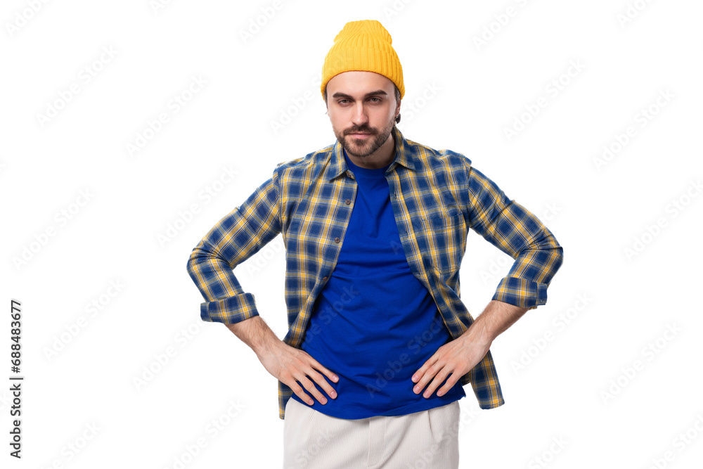 well-groomed authentic young european brunette man with a brutal beard and mustache dressed in a yellow hat and blue shirt