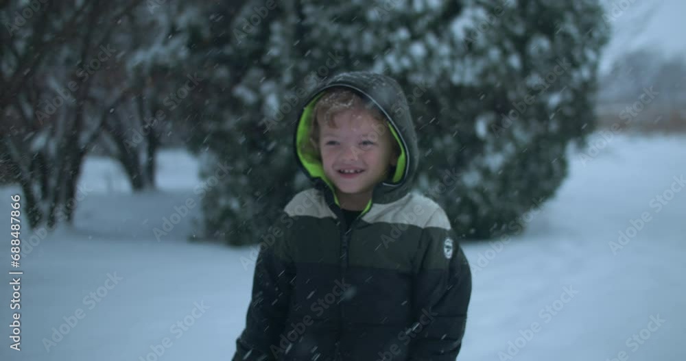 Happy kid on Christmas morning playing in snow. Young boy smiles as slow motion snow flakes falls in cinematic slow motion. Happy kid on Christmas morning playing in snow. Young boy smiles as slow motion snow flakes falls in cinematic slow motion.