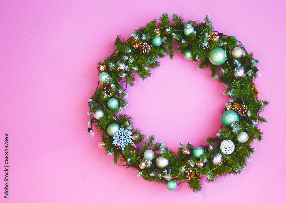decorative festive wreath with green and white christmas toys on Pink background