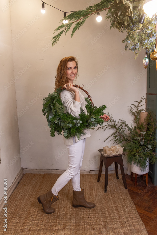 Portrait of young woman holding asymmetrical green Christmas wreath made of natural materials Portrait of young woman holding asymmetrical green Christmas wreath made of natural materials