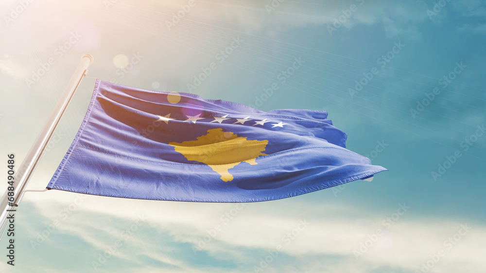 Kosovo national flag waving in beautiful sky. The symbol of the state on wavy silk fabric.