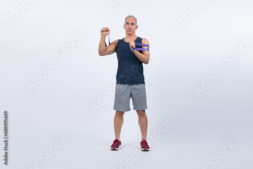 Full body length shot athletic and sporty senior man with fitness resistance band on isolated background. Healthy active physique and body care lifestyle after retirement. Clout
