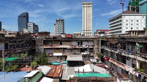 Drone footage above the courtyard of an old creepy building in Phnom Penh city, Cambodia. Camera moves fowards showing homes  and the brand new towers in the background brings a contrast 1-2 photo