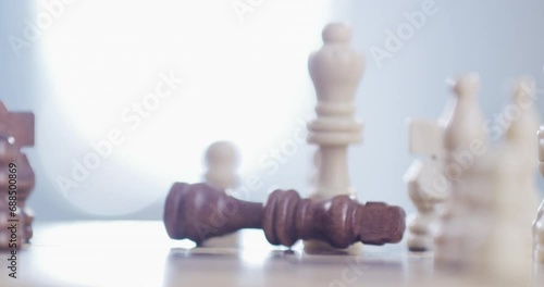 Person, hand and chess piece in defeat on board for king, checkmate or endgame on table at home. Closeup of people playing strategic match, challenge or victory in sports competition on chessboard photo