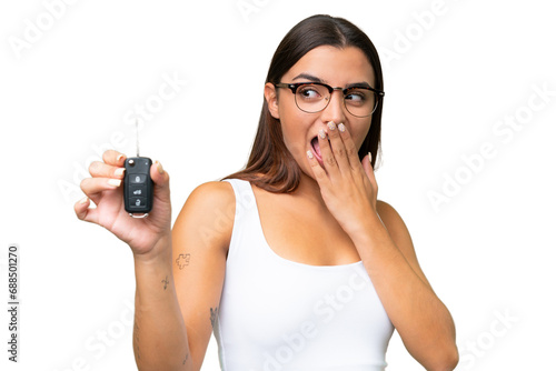 Young caucasian woman holding car keys isolated on green chroma background background with surprise and shocked facial expression photo
