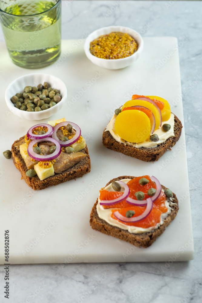 assorted toasts with dark rye bread, herrings, smoked salmon and capers. copy space. Vertical