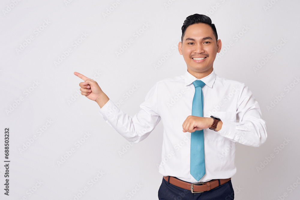Smiling happy young Asian businessman employee company lawyer wearing a formal shirt tie watch looking aside while pointing finger at empty space isolated on white background Smiling happy young Asian businessman employee company lawyer wearing a formal shirt tie watch looking aside while pointing finger at empty space isolated on white background