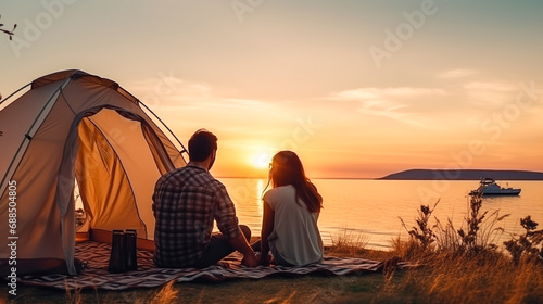 Young couple in love on vacation in a tent on the lake shore at sunset. Concept of travel, hiking, relaxation and free time. Romantic date, camping trip, adventure, nature exploring