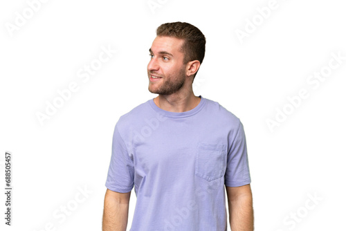 Young handsome caucasian man isolated on green chroma background looking to the side and smiling