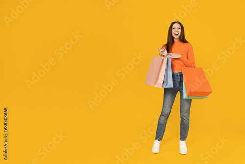 Young girl with shopping bags on a yellow background.
