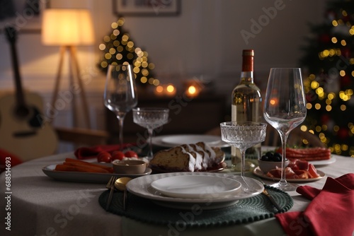 Christmas table setting with bottle of wine  appetizers and dishware in room
