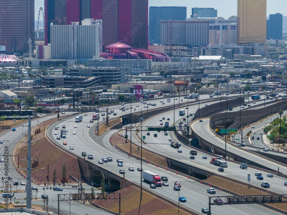 High-angle view of a vibrant cityscape with a complex highway interchange, modern skyscrapers, and a Ferris wheel in Las Vegas, USA.